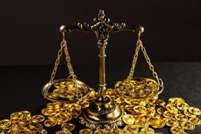 天秤の皿からコインが溢れている様子が写った画像